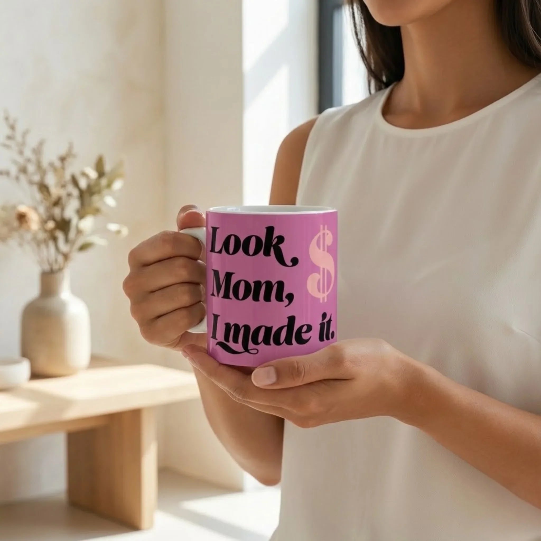 Person holding a pink mug with text in a bright indoor setting